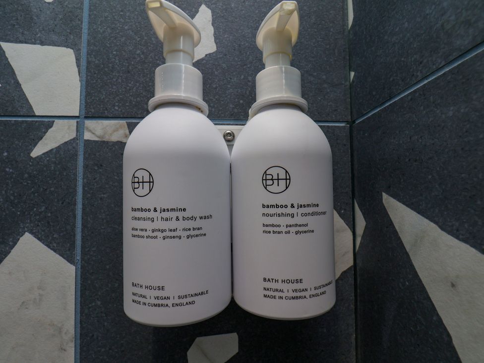 Body wash and conditioner bottles mounted in a bathroom at Apartment Blue in Whitby