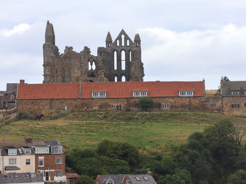 Ruins of a historic building with grass and houses at Apartment Blue in Whitby