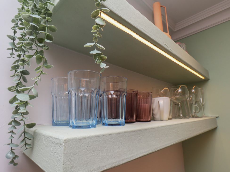 A shelf with various glasses in a kitchen at Apartment Green in Whitby
