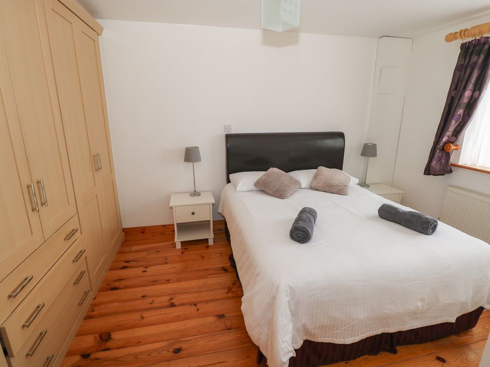 A bedroom with a bed and wardrobe at Islands Inn Louisburgh, County Mayo