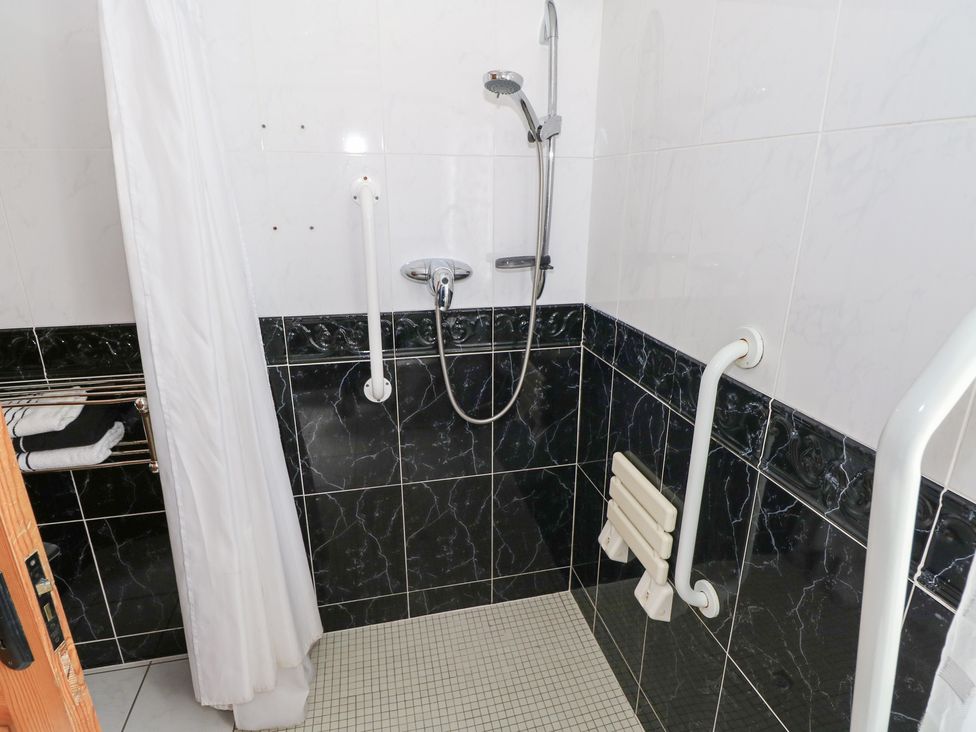 A bathroom with a shower and grab bars at Islands Inn in Louisburgh, County Mayo