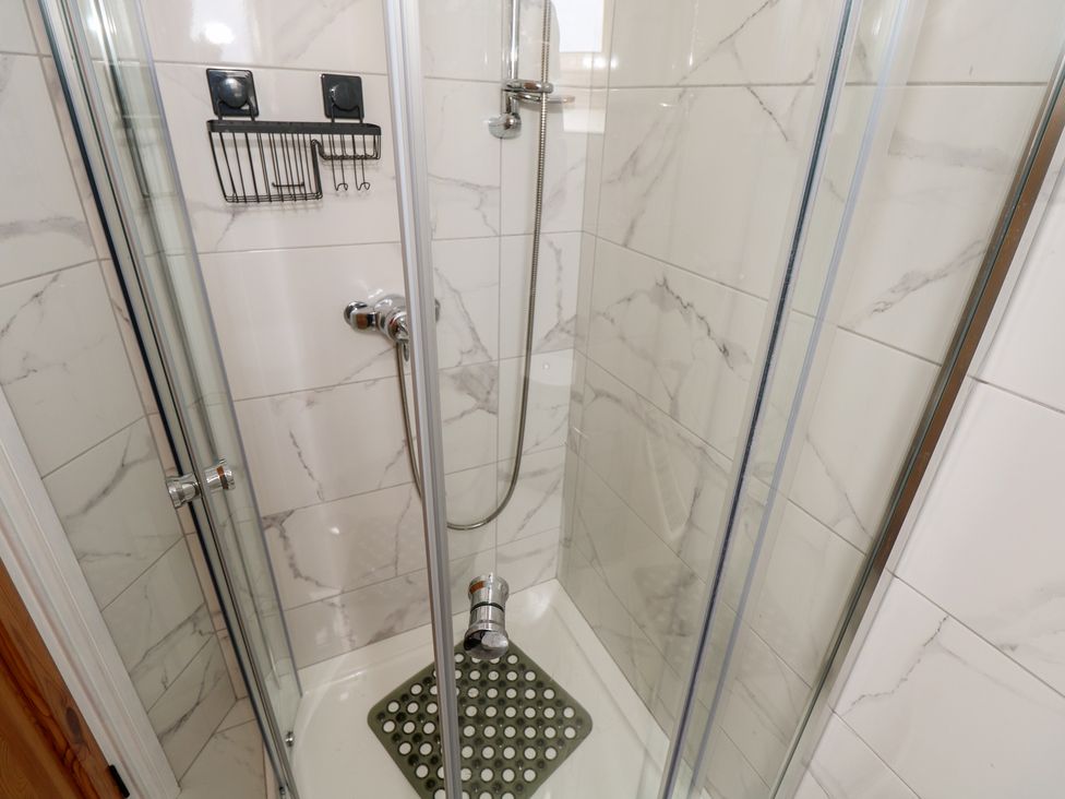 A shower with glass doors and a shower mat at Islands Inn, Louisburgh, County Mayo