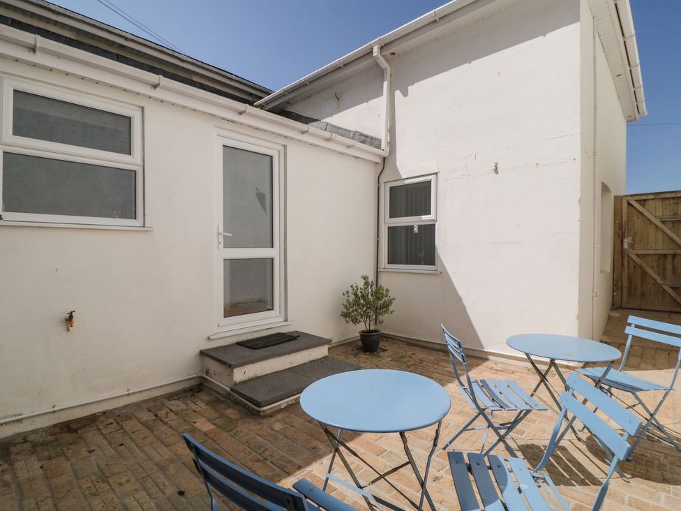 An outdoor area with a door and blue furniture at Broadsands Cottage in Paignton