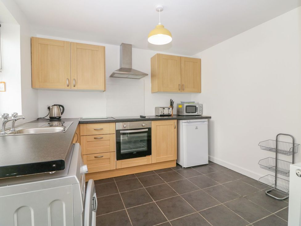 A kitchen with wooden cupboards and appliances at Broadsands Cottage in Paignton