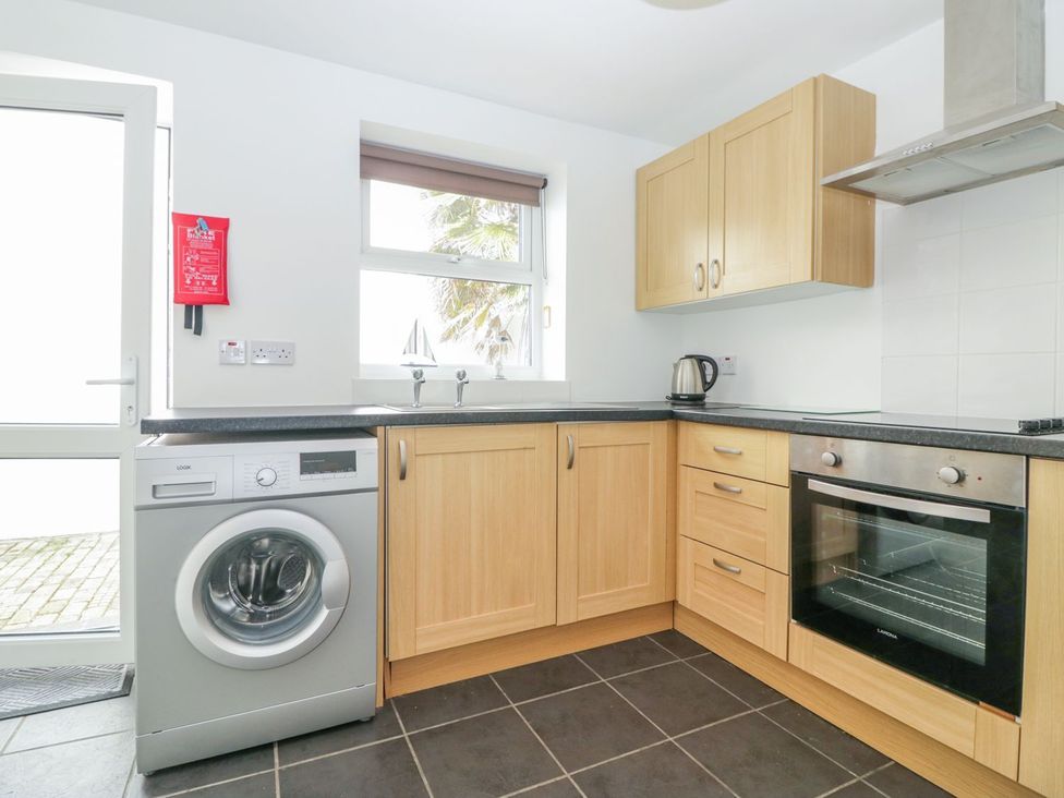 A kitchen with a washing machine and oven at Broadsands Cottage in Paignton