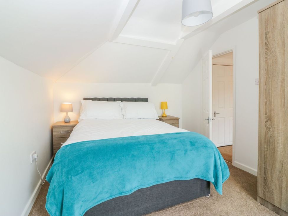 A bedroom with a bed and bedside lamp at Broadsands Cottage in Paignton