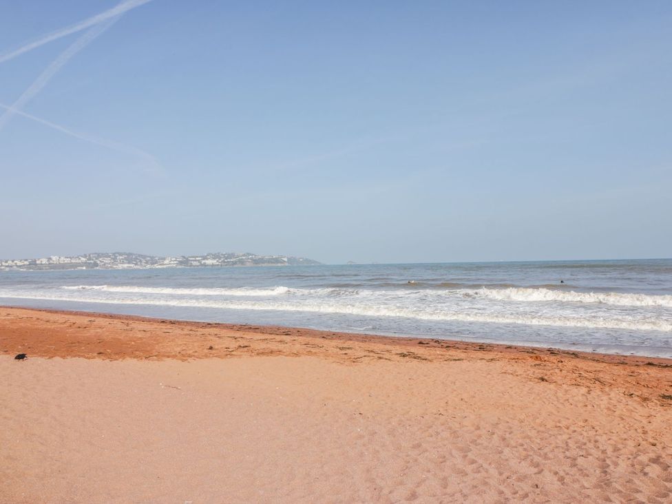 A beach with sand and ocean waves at Broadsands Cottage Paignton