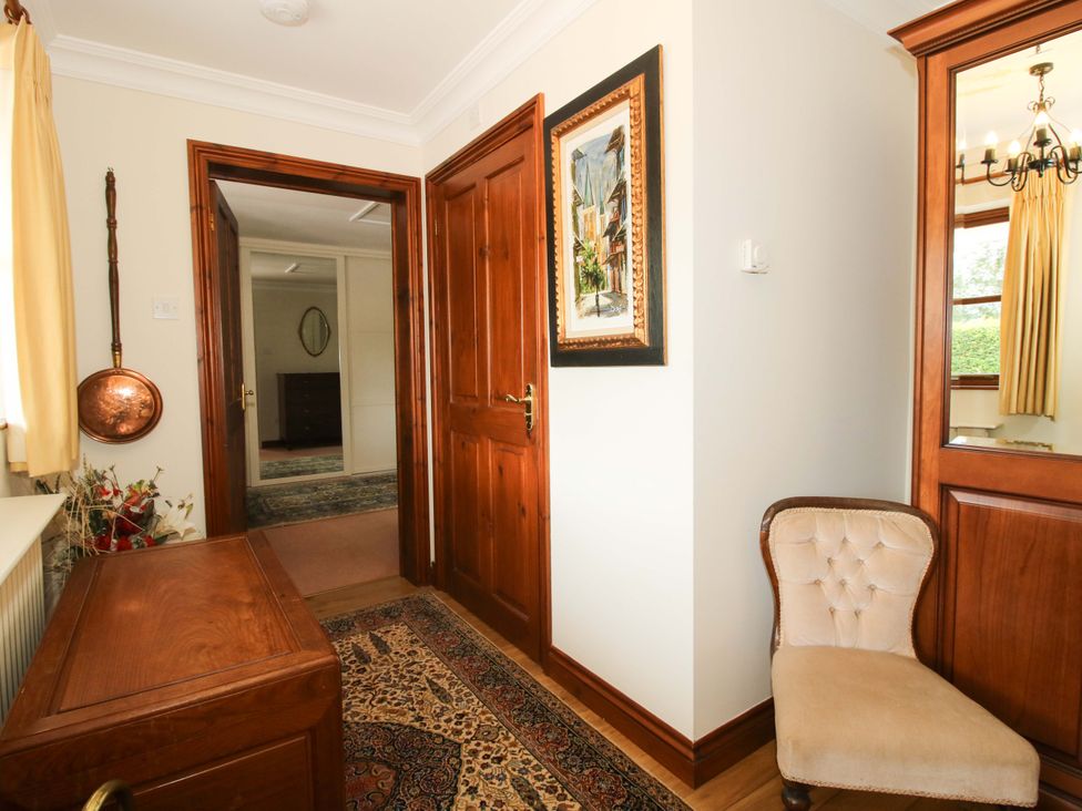 A hallway with doors and a chair at Willow Cottage in Lydbury North