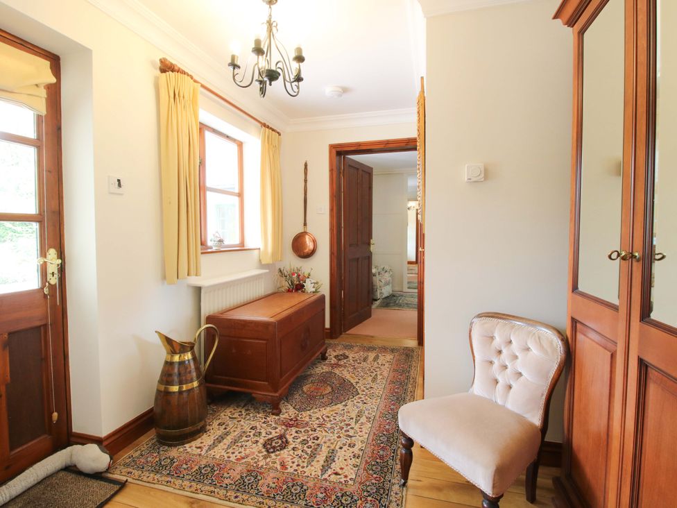 A hallway with a rug and a chair at Willow Cottage in Lydbury North
