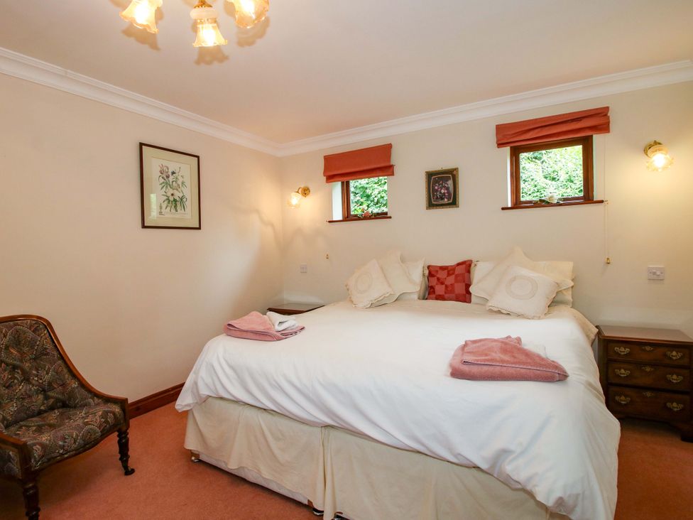 A bedroom with a bed and chair at Willow Cottage in Lydbury North