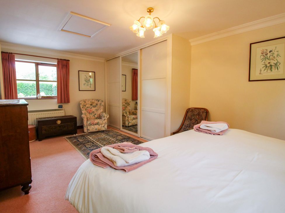 A bedroom with a bed and armchair at Willow Cottage in Lydbury North
