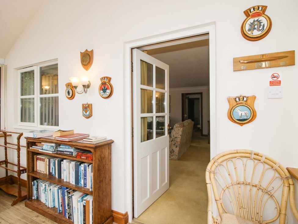 A hallway with a bookshelf and wall decorations at Willow Cottage in Lydbury North
