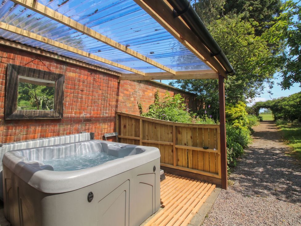 An outdoor area with a hot tub and wooden fence at Apple Bough Cottage in Hereford