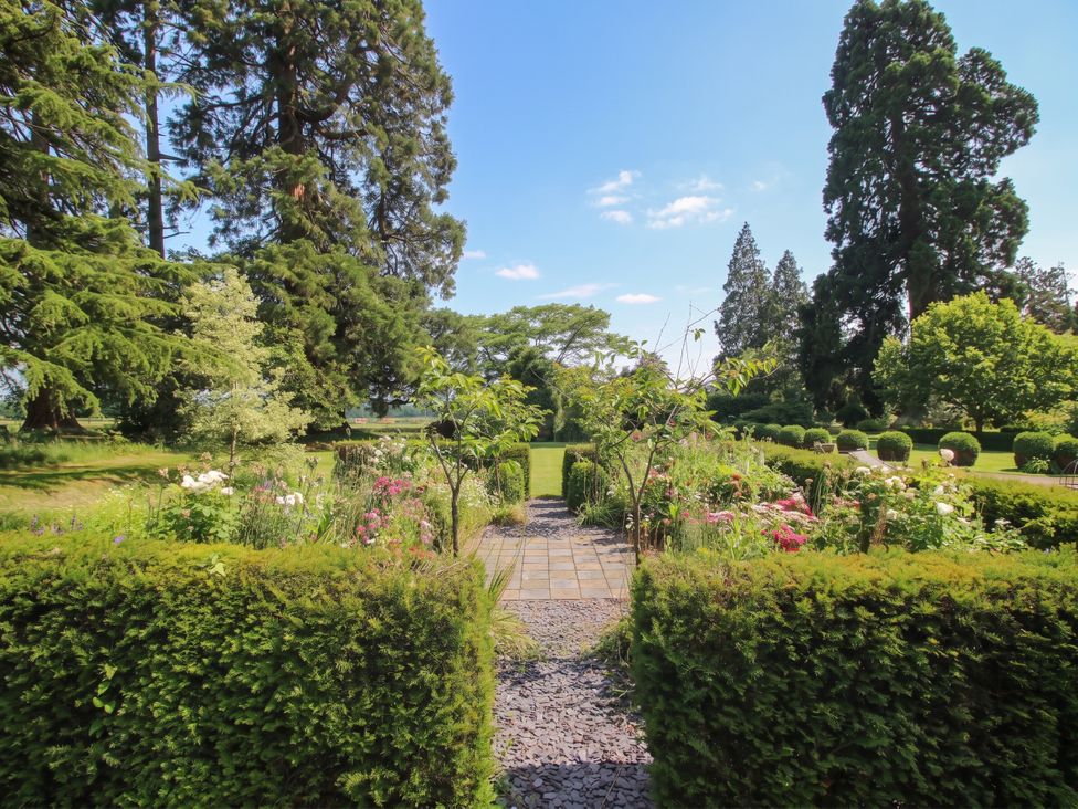 A garden with flowers and trees at Apple Bough Cottage in Hereford