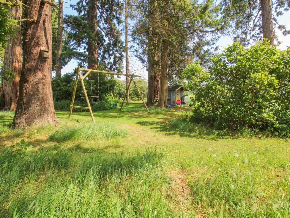 A garden with a swing set and trees at Apple Bough Cottage Hereford