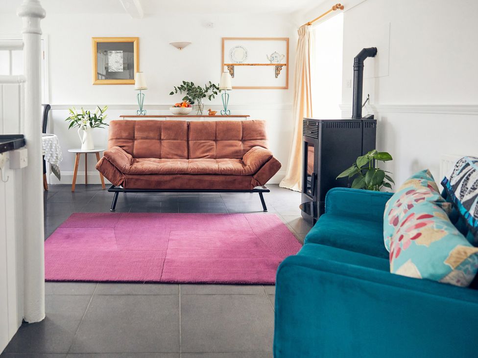 A living room with a brown sofa and a green plant at Apple Bough Cottage in Kinnersley