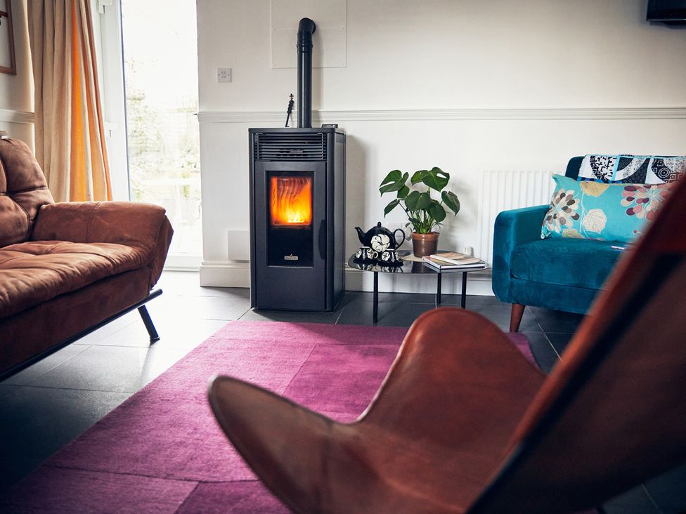 A living room with a stove and seating area at Apple Bough Cottage in Kinnersley