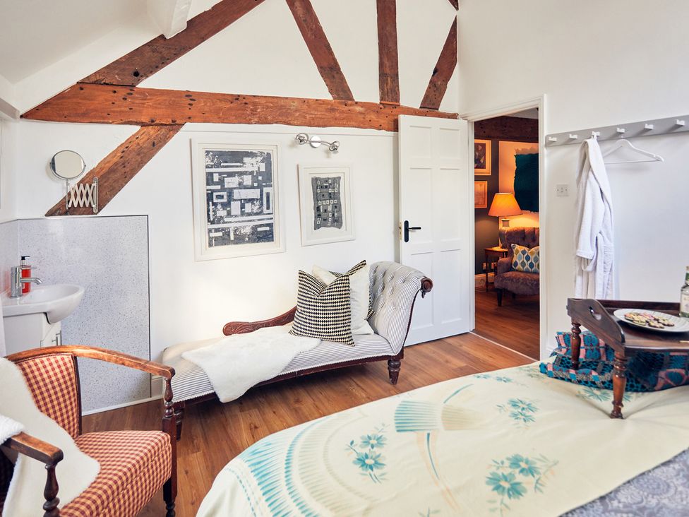 A bedroom with an armchair and bed at Apple Bough Cottage in Kinnersley