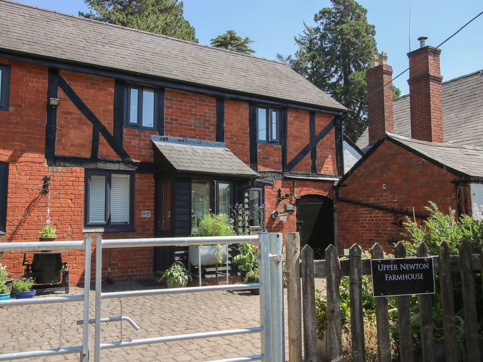 An outdoor view of a brick house with plants at Upper Newton Farmhouse in Kinnersley near Weobley