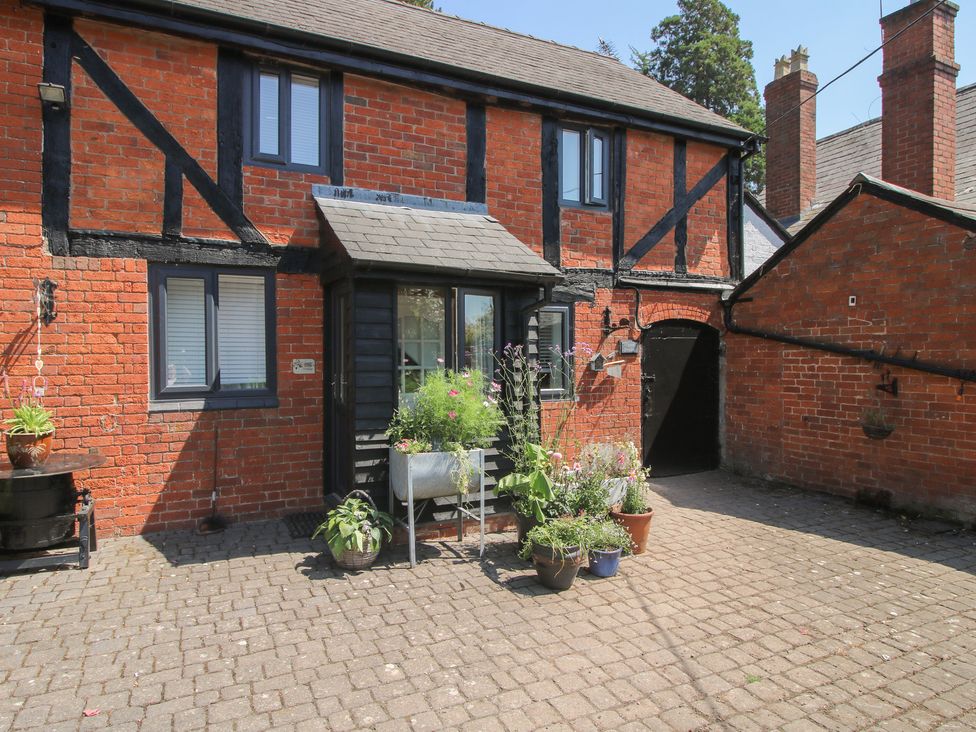 An outdoor area with potted plants and brick buildings at Apple Bough Cottage in Kinnersley near Weobley