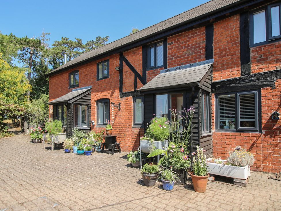 An outdoor area with potted plants and a brick wall at Apple Bough Cottage in Kinnersley near Weobley