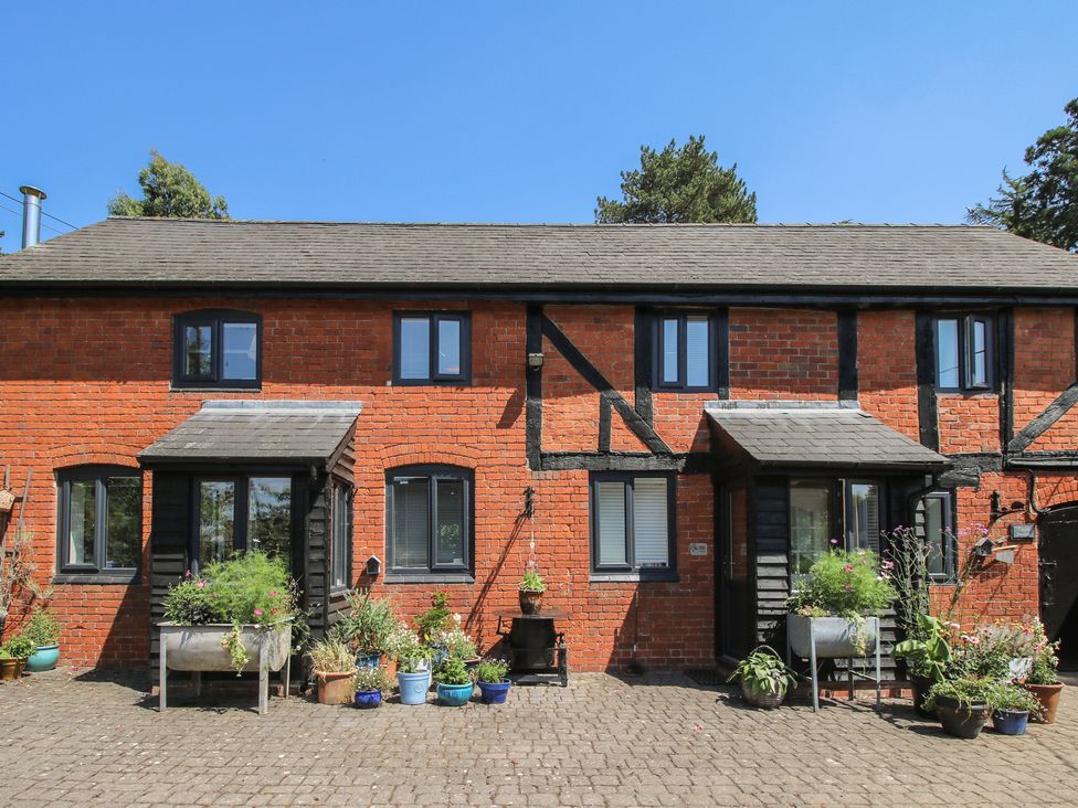 A facade of a cottage with flower pots in front at Apple Bough Cottage Kinnersley near Weobley