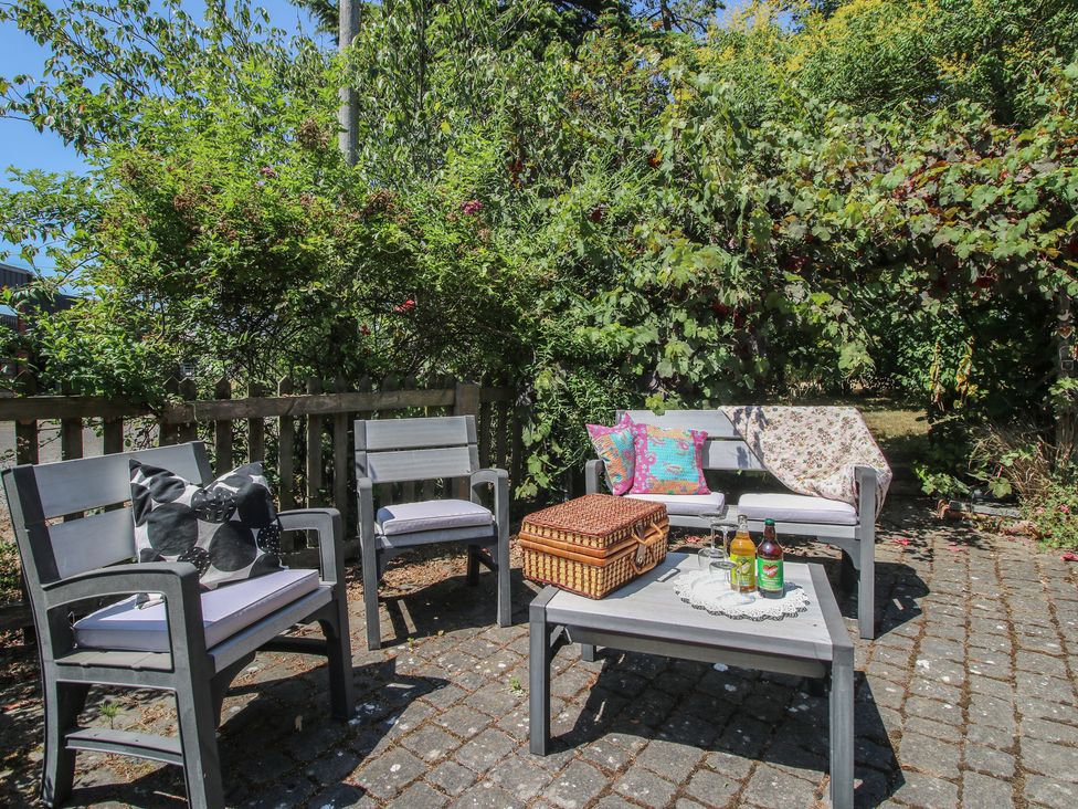 A garden seating area with a table and picnic basket at Apple Bough Cottage in Kinnersley near Weobley