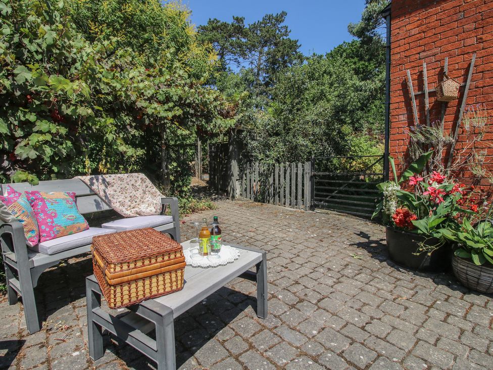 A garden with a bench, table, flowers, and a basket at Apple Bough Cottage, Kinnersley near Weobley