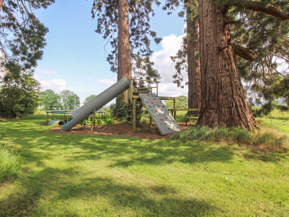 A play structure with a slide and climbing wall in the garden at Chess Cottage Hereford