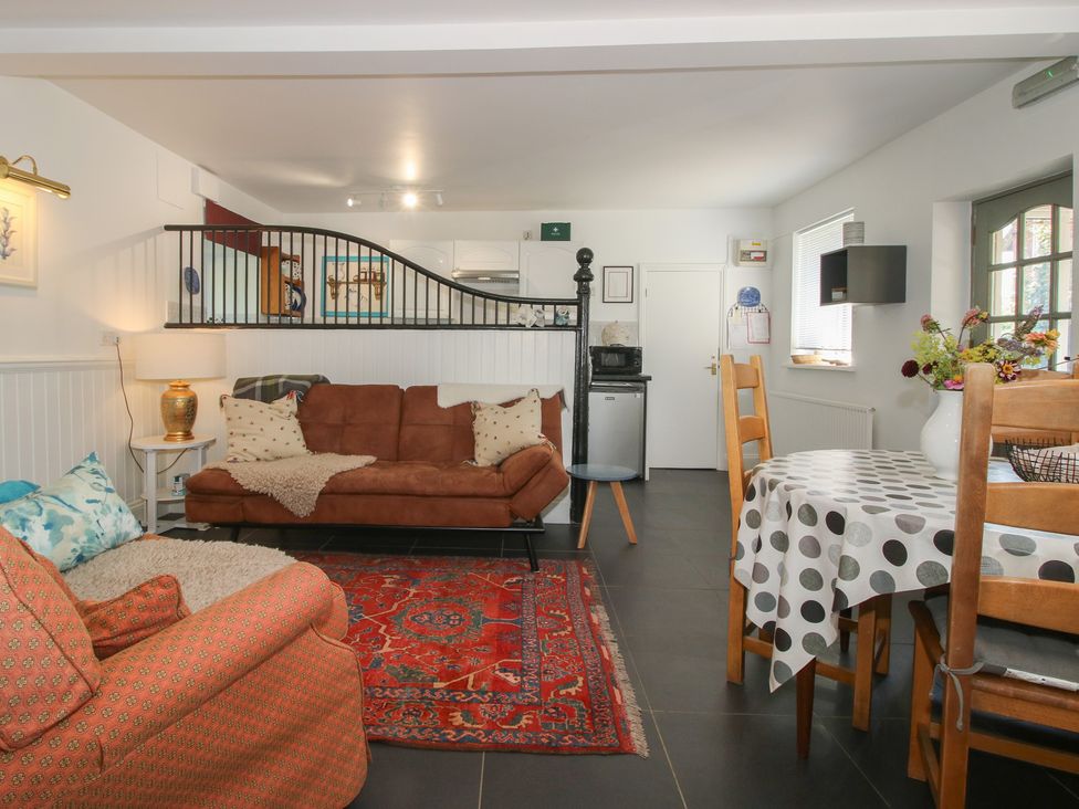A living room with a sofa, table, and kitchen unit at Chess Cottage in Weobley