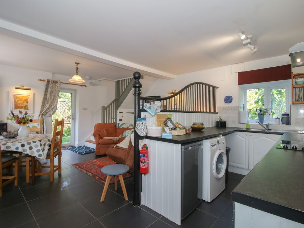 A kitchen with a dining area and washing machine at Chess Cottage in Weobley
