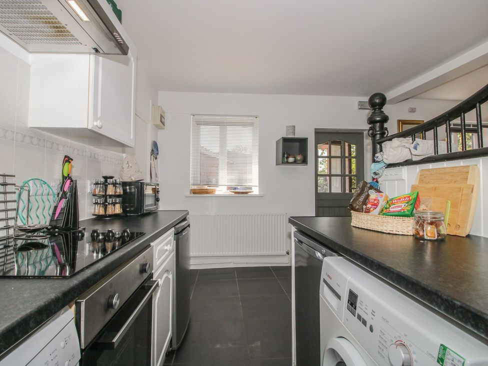 A kitchen with a stove, microwave, and washing machine at Chess Cottage in Weobley