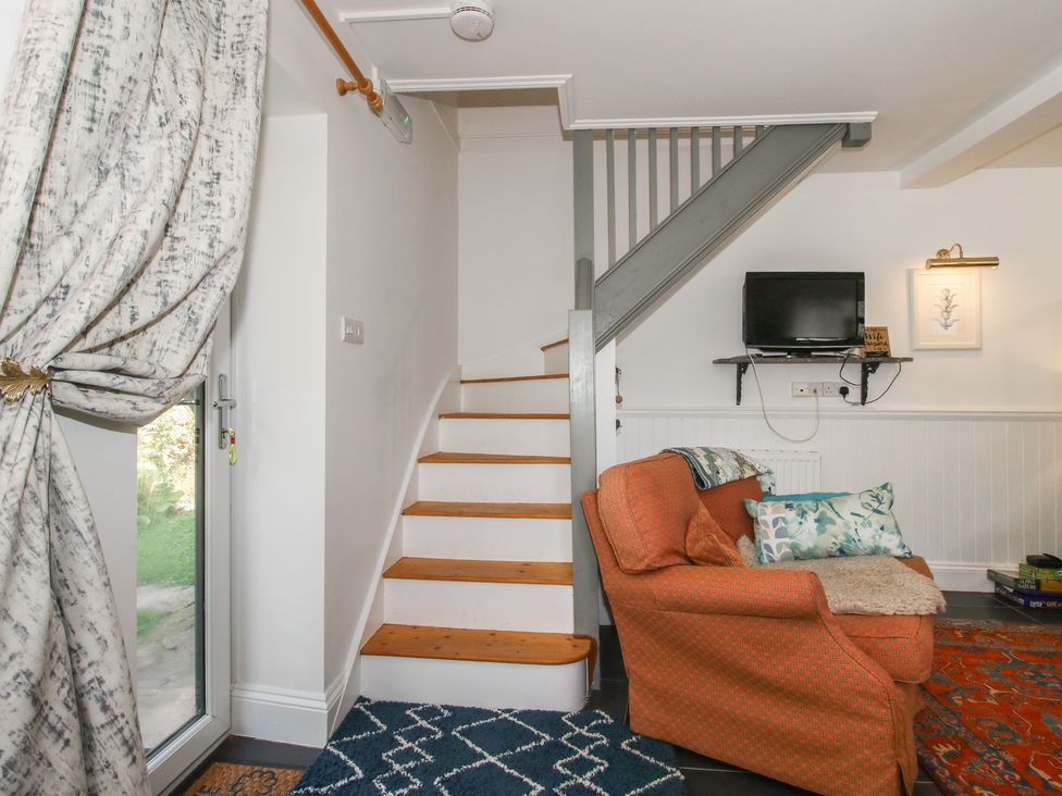 A living room with a sofa and a staircase at Chess Cottage in Weobley