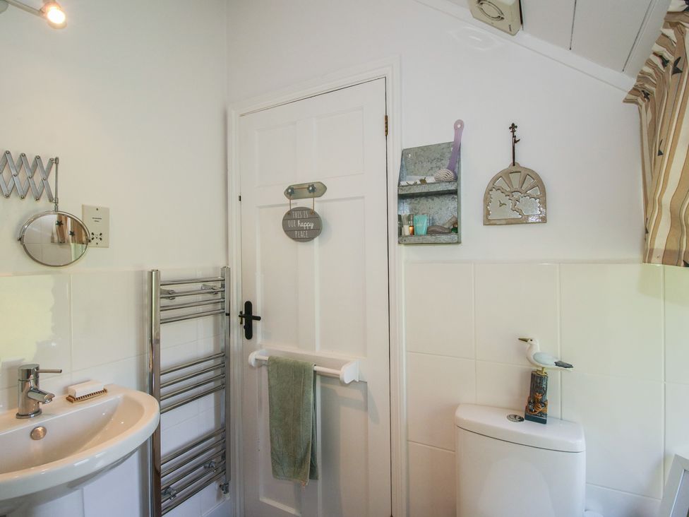 A bathroom with a sink, towel rack, and decorative items at Chess Cottage in Weobley