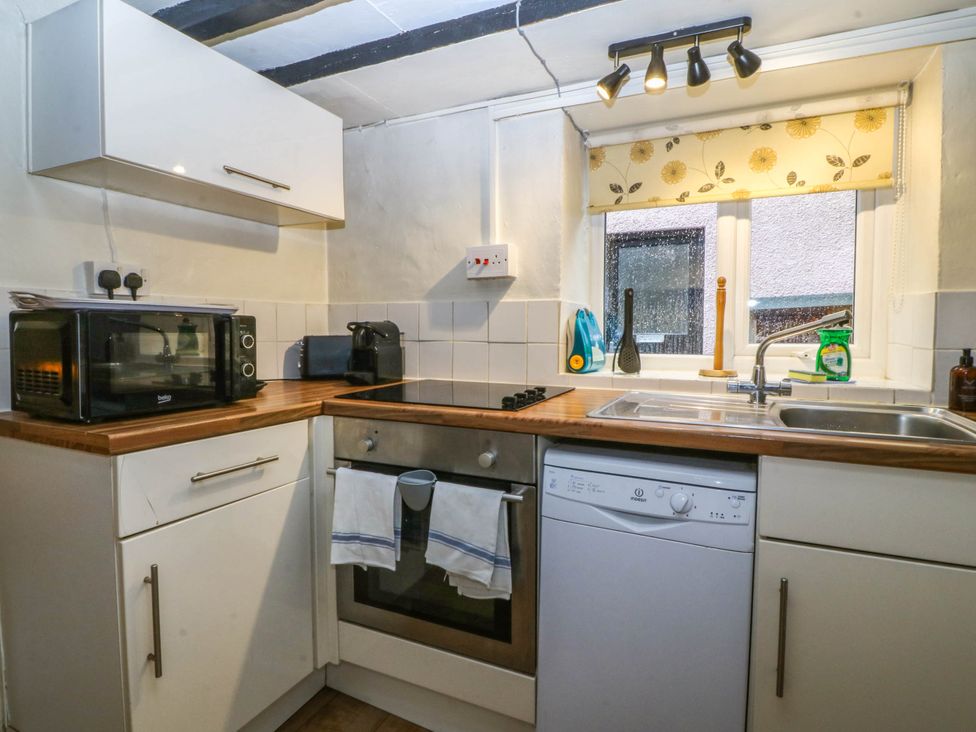A kitchen with microwave, kettle, oven, sink and dishwasher at Bwthyn Bach in Pentrefelin