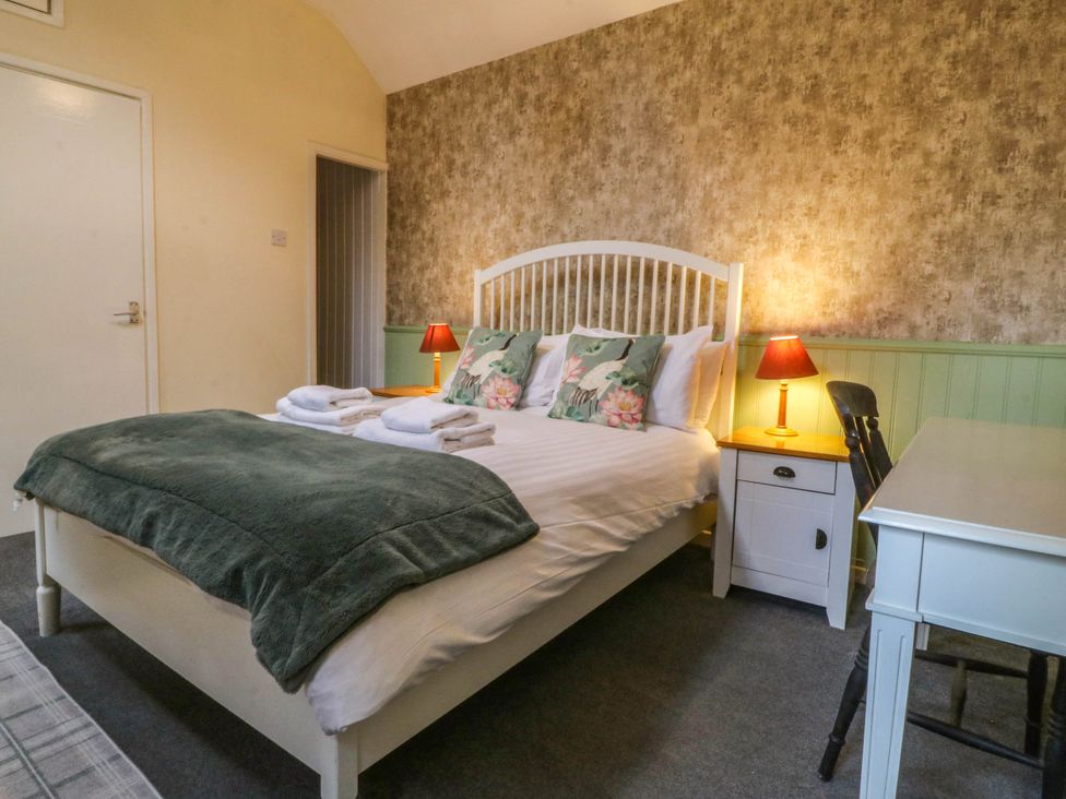 A bedroom with a bed and desk at Bwthyn Bach in Pentrefelin