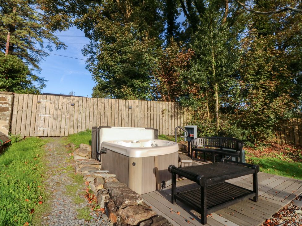 An outdoor area with a hot tub and seating at Bwthyn Bach in Pentrefelin