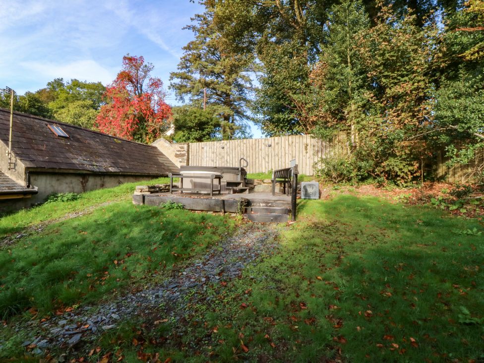 A garden with a hot tub and wooden bench at Bwthyn Bach in Pentrefelin