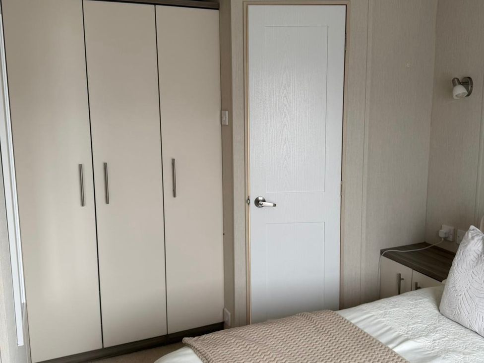 A bedroom with a wardrobe and a bed at Trecco Bay holiday park, Porthcawl