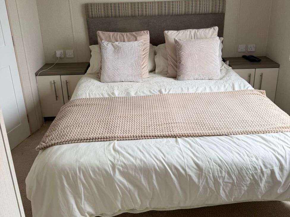 A bed with pillows and a bedside table at Trecco Bay holiday park, Porthcawl