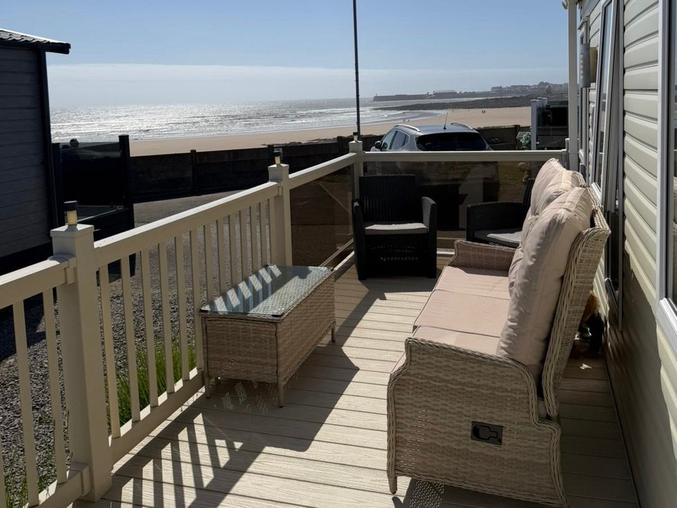 A balcony with seating and table overlooking the ocean at Trecco Bay holiday park, Porthcawl