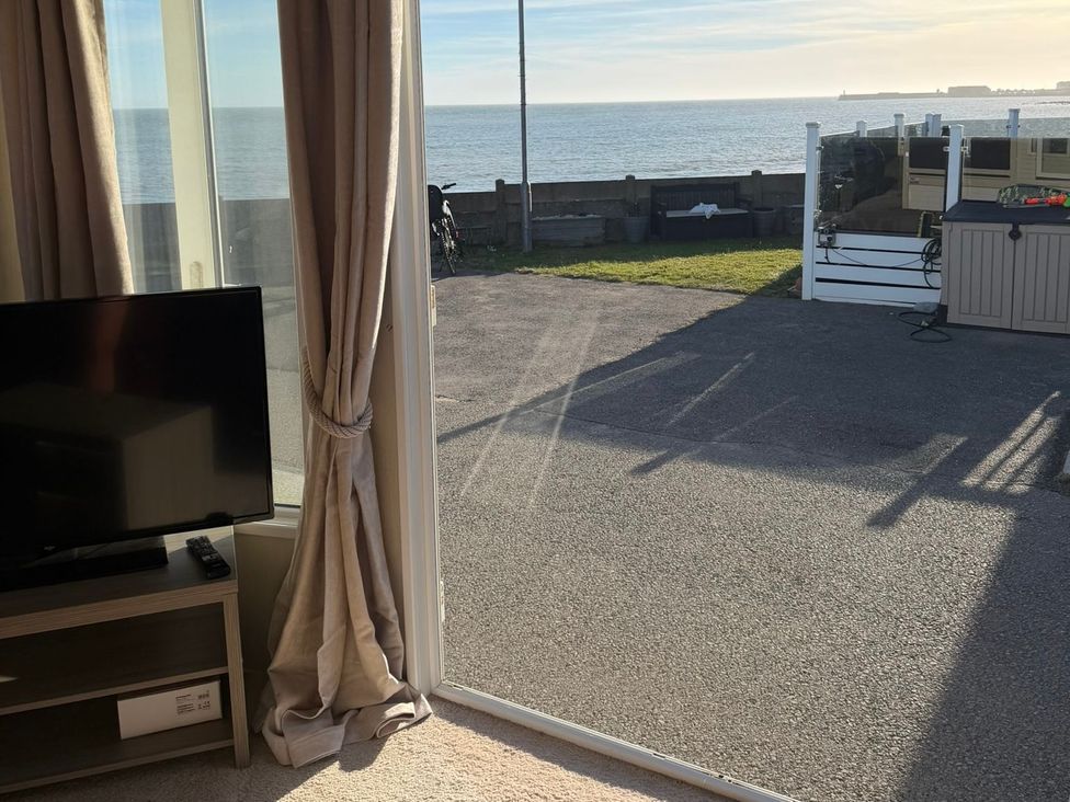 A living room with a television and curtains at Trecco Bay holiday park, Porthcawl