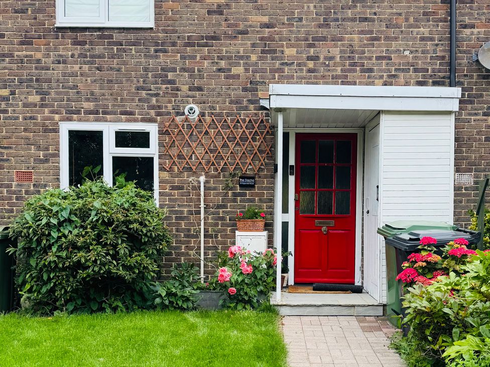 An exterior view of a house with a red door and flower pots at The Dacha in Winchester