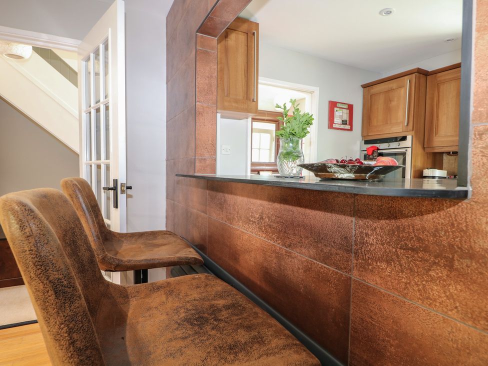 A kitchen with bar stools and a fruit bowl at The Dacha in Winchester