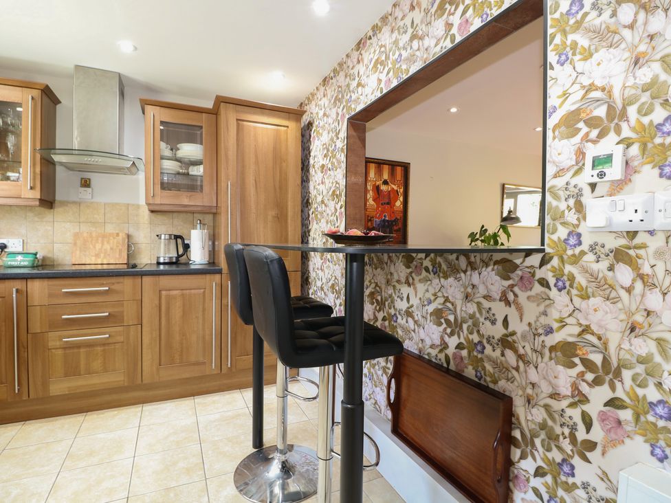 A kitchen with wooden cabinets and bar stools at The Dacha in Winchester