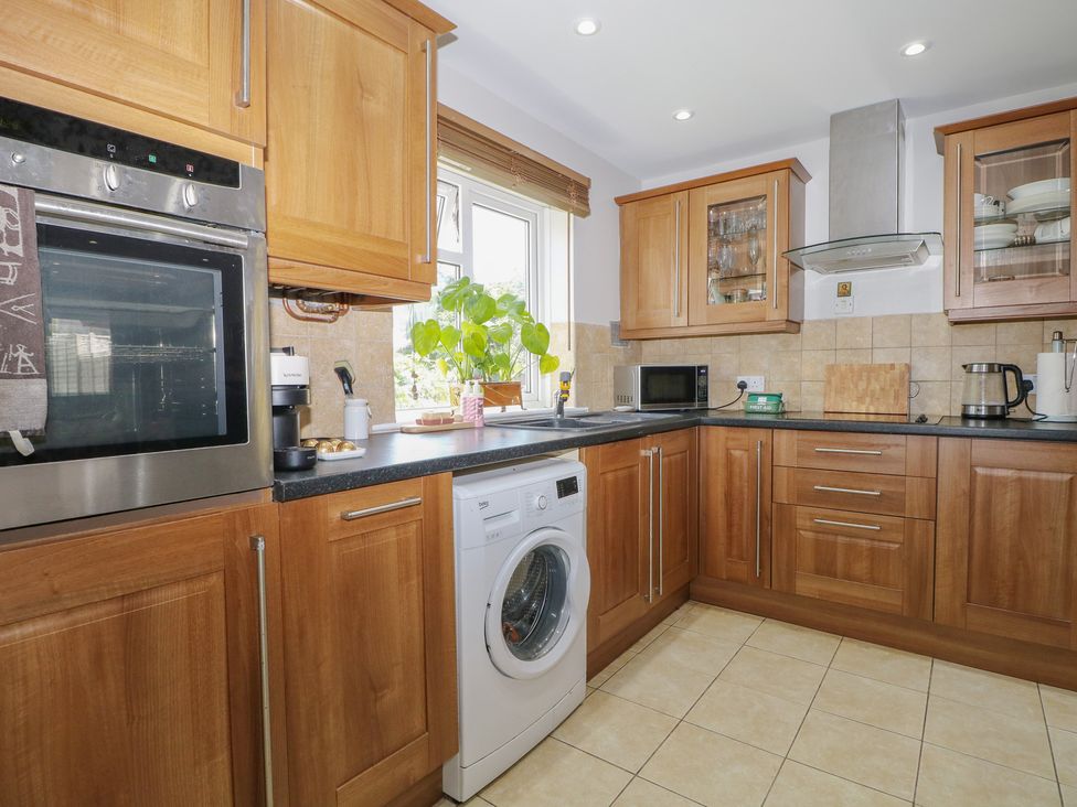 A kitchen with various appliances and wooden cabinets at The Dacha in Winchester