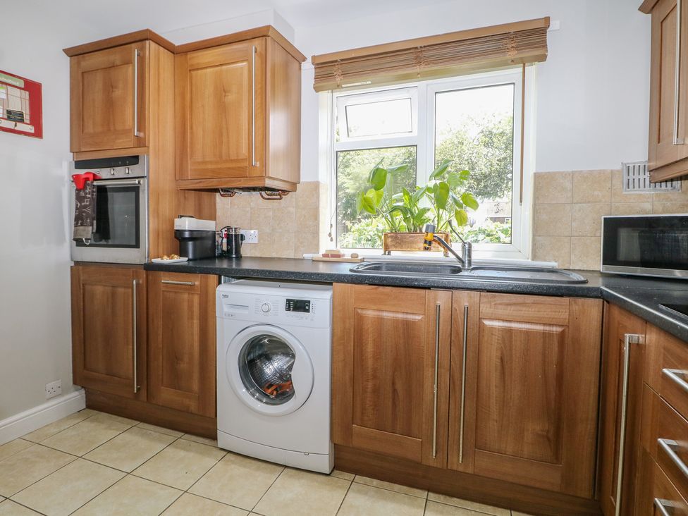 A kitchen with cabinets, a washing machine, and a window at The Dacha in Winchester