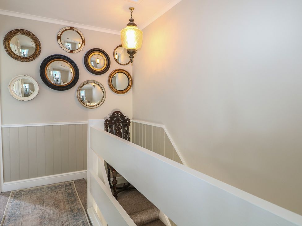 A hallway with mirrors on the wall and a chair at The Dacha in Winchester