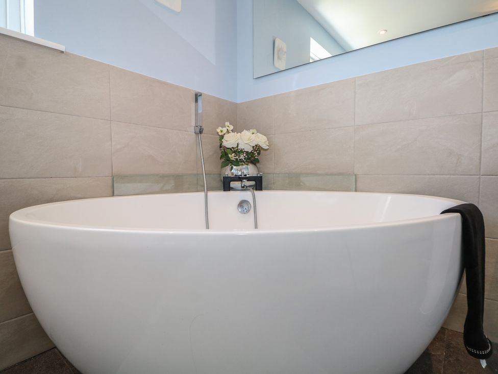 A bathtub with a faucet and plant in a bathroom at The Dacha in Winchester