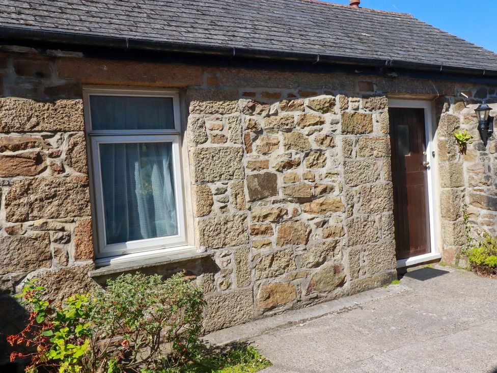 An exterior view of a cottage with a stone wall and window at Chyancrowse in Penzance
